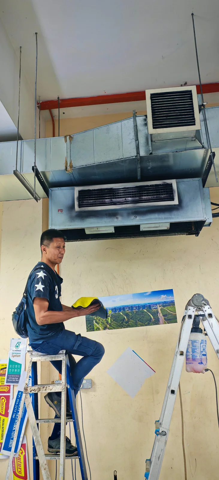 SKN RAKAN technician working on a ceiling-mounted air conditioning system